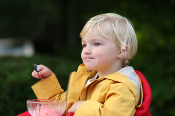 Little girl eating yoghurt in outdoors cafe