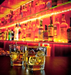 glasses of whiskey with ice on bar table on warm atmosphere