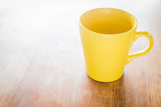 Yellow ceramic cup on wooden table