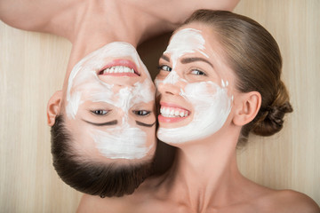 Two beautiful girls applying facial cream mask and beauty treatm