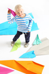 Mały chłopiec  trzyma w dłoni papierowy samolot