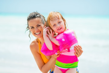 Portrait of mother and baby girl listening sound of sea in shell