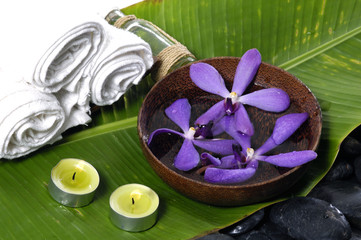 An orchid, towels, and candles on leaf