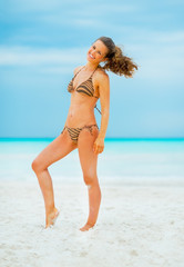 Naklejka premium Full length portrait of happy young woman on beach