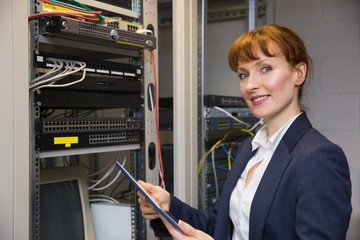 Pretty technician using tablet pc while fixing server