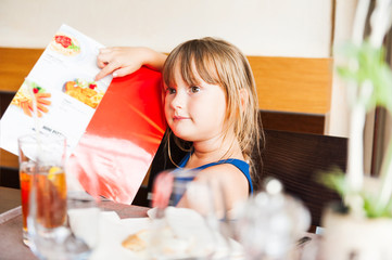 Cute little giel choosing her meal in a kid's menu