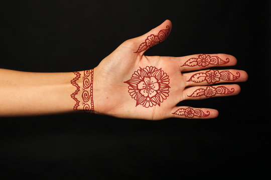 hand with mehendi on black background