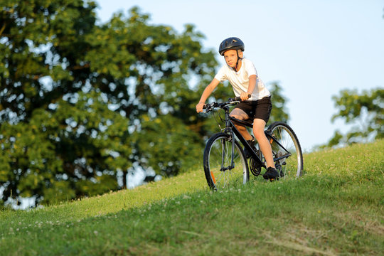 Teenage boy rides a bike from the hill in city park