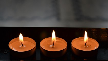 Fototapeta na wymiar Three burning church candles on stand
