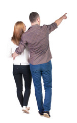 Back view of walking young couple (man and woman) pointing.