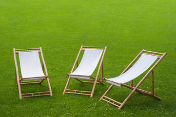 three folding chairs in a green park