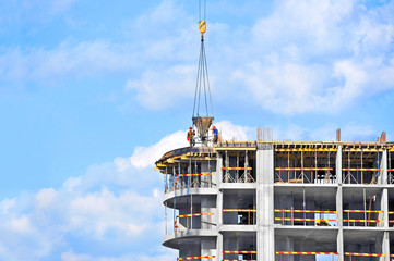 Crane lifting concrete mixer container against blue sky