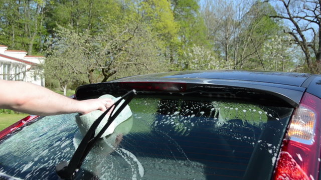 Closeup of man with soapy sponge clean wash back car glass