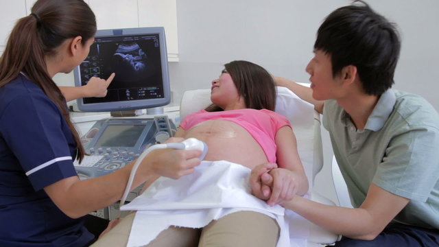 Pregnant Woman And Partner Having Ultrasound Scan