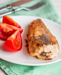 grilled fish with tomato on a plate, fork and knife