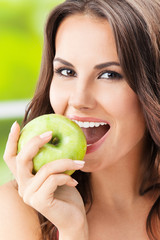 Young woman eating apple, outdoors