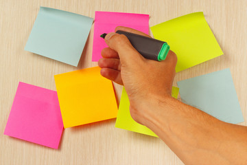 Hand writes a green marker on the sticker on wooden noticeboard