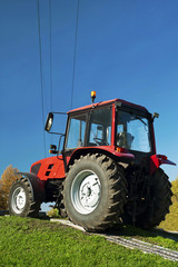 Modern red tractor on a blue sky background.