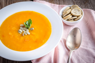 Portion of pumpkin cream soup on the wooden table