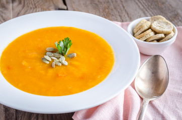 Portion of pumpkin cream soup on the wooden table