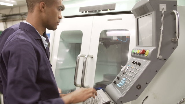Engineer Teaching Apprentice To Use Computerized Lathe
