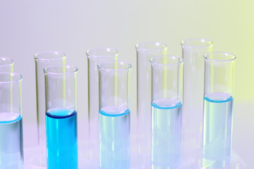 Test-tubes with blue liquid on lilac background