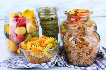 Colorful pasta in glass jars on wooden background