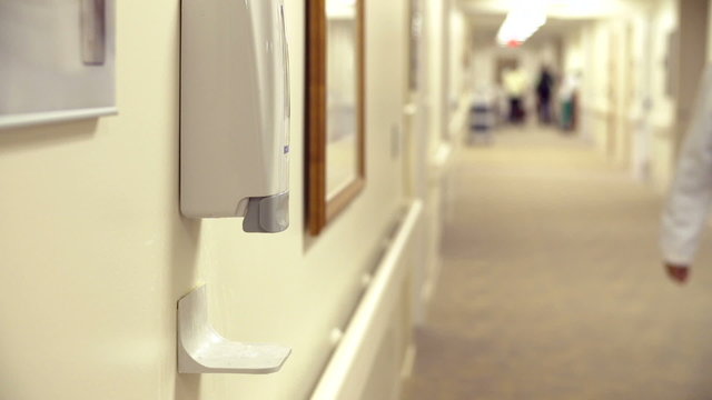 Male Doctor Using Hand Sanitizer In Hospital