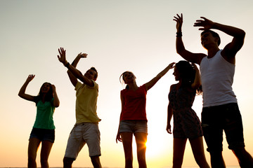 Obraz premium smiling friends dancing on summer beach