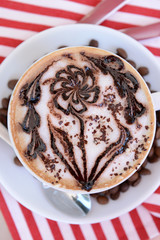 Cup of coffee with cute drawing on table, close up