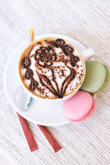 Cup of coffee with cute drawing on table, close up