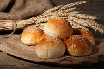 Tasty buns with sesame on wooden background