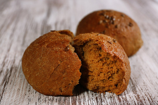 Tasty brown buns on color wooden background