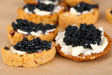 Slices of bread with butter and black caviar on paper