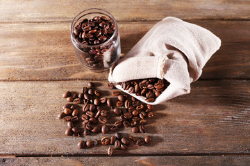 Coffee beans in fabric bag and glass jar on wooden background