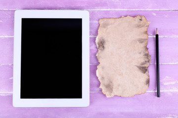 Tablet, piece of paper and pencil on wooden background