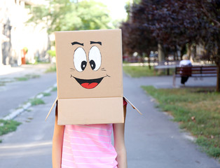 Woman with cardboard box on her head with happy face, outdoors
