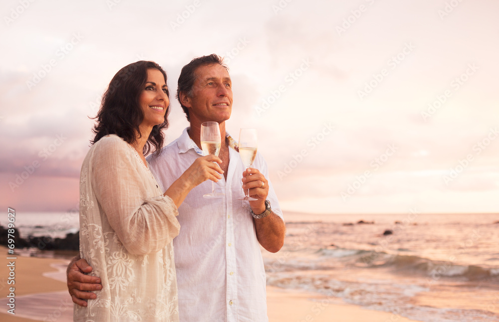 Wall mural romantic couple drinking champagne on the beach at sunset