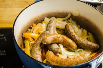 Sausage links cooking with peppers and onions