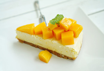 Mango cheesecake on white plate with fork