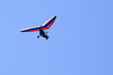 Fototapeta na wymiar Trike (hang glider with a motor) against the blue sky.