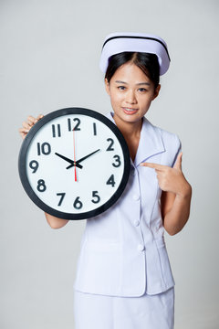 Asian young nurse point to a clock