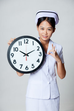 Asian young nurse show OK with a clock