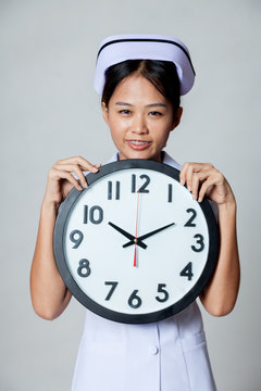 Asian young nurse smile with a clock