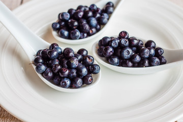 blueberries in the spoons on a white plate