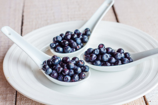 blueberries in the spoons on a white plate