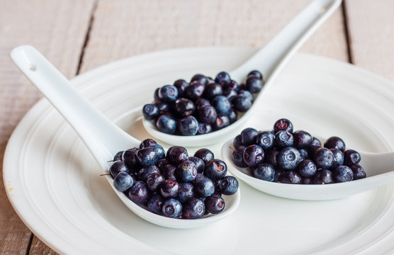 blueberries in the spoons on a white plate, horizontally