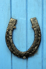 black horseshoe nailed to blue door