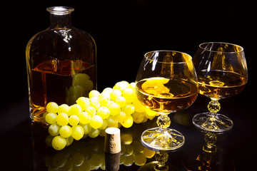 Bottle of brandy and two glasses and grapes