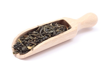 Dried green tea on wooden spoon. White background